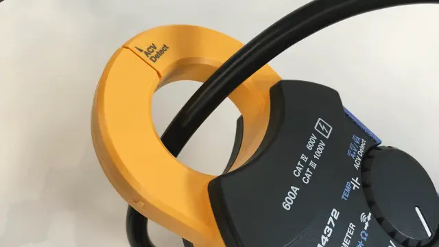 電線が、クランプ電流計のセンサの中に収まるように、はさんでください